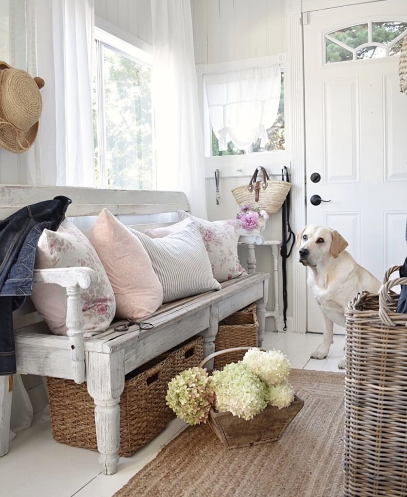 A shabby chic entryway with pink pillows.