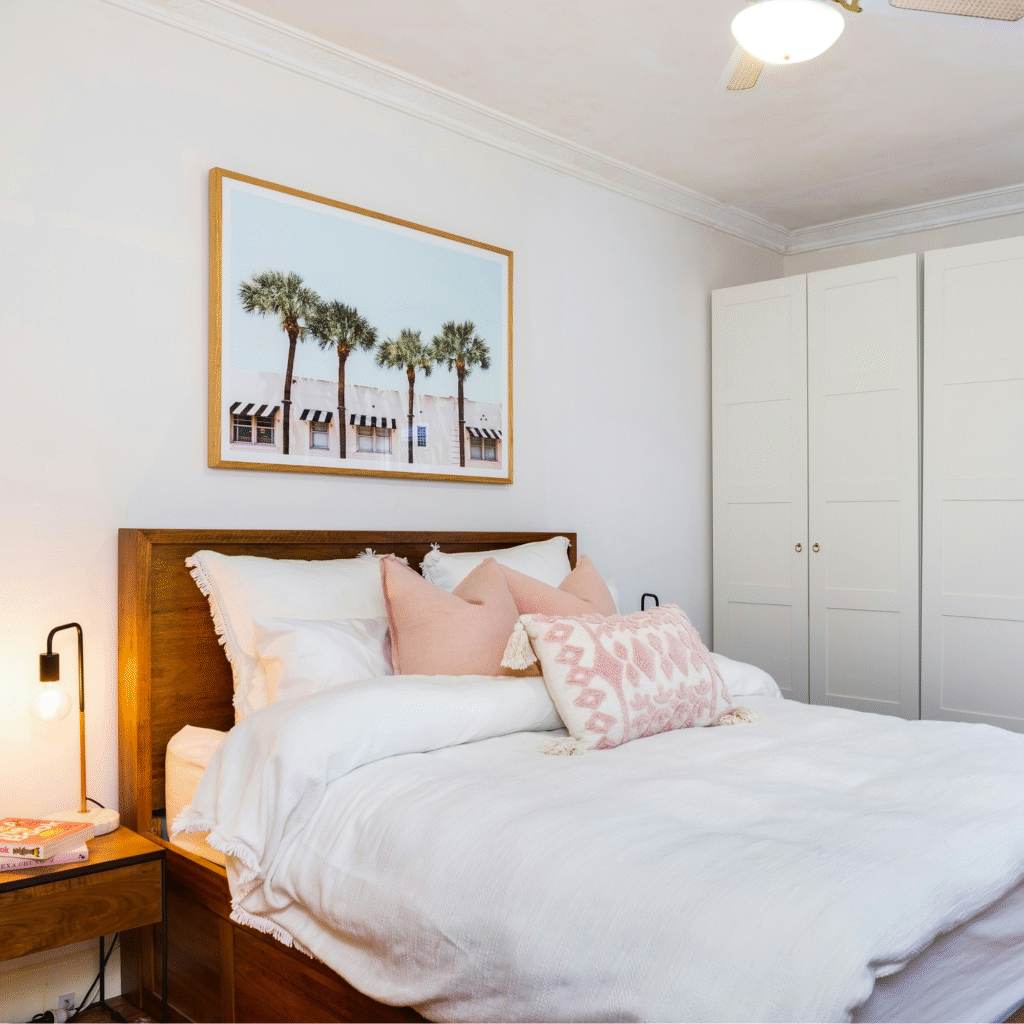 A bedroom with white and pink bedding.