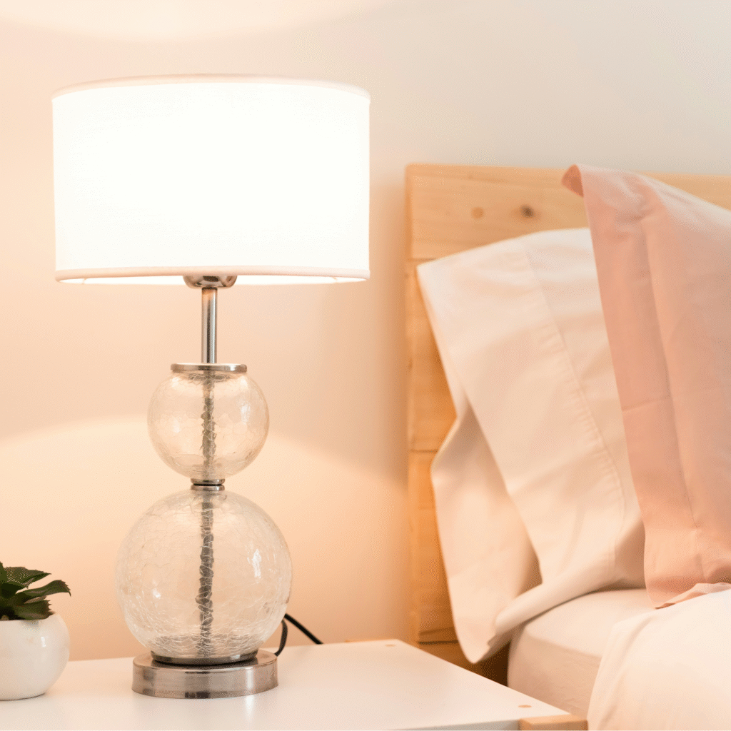 A glass lamp with pink bedding.