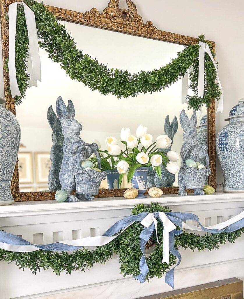 Stone bunny figurines with greenery and blue ribbon garlands.