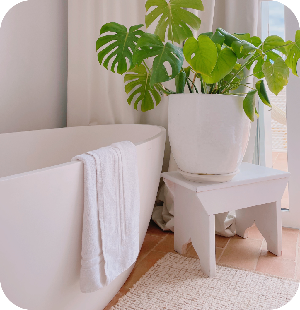 A white bathroom with a beige bathroom rug.