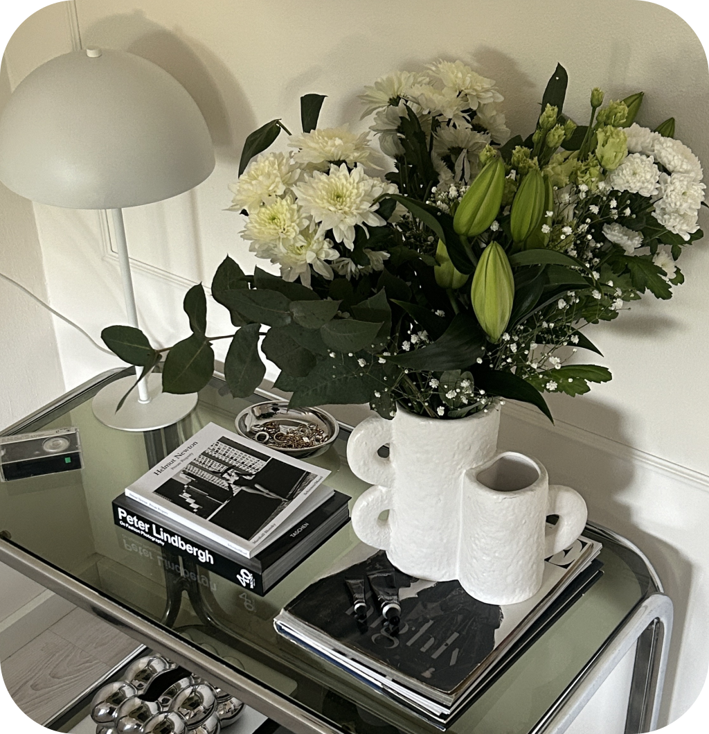 A modern entryway with a glass console table and flowers.