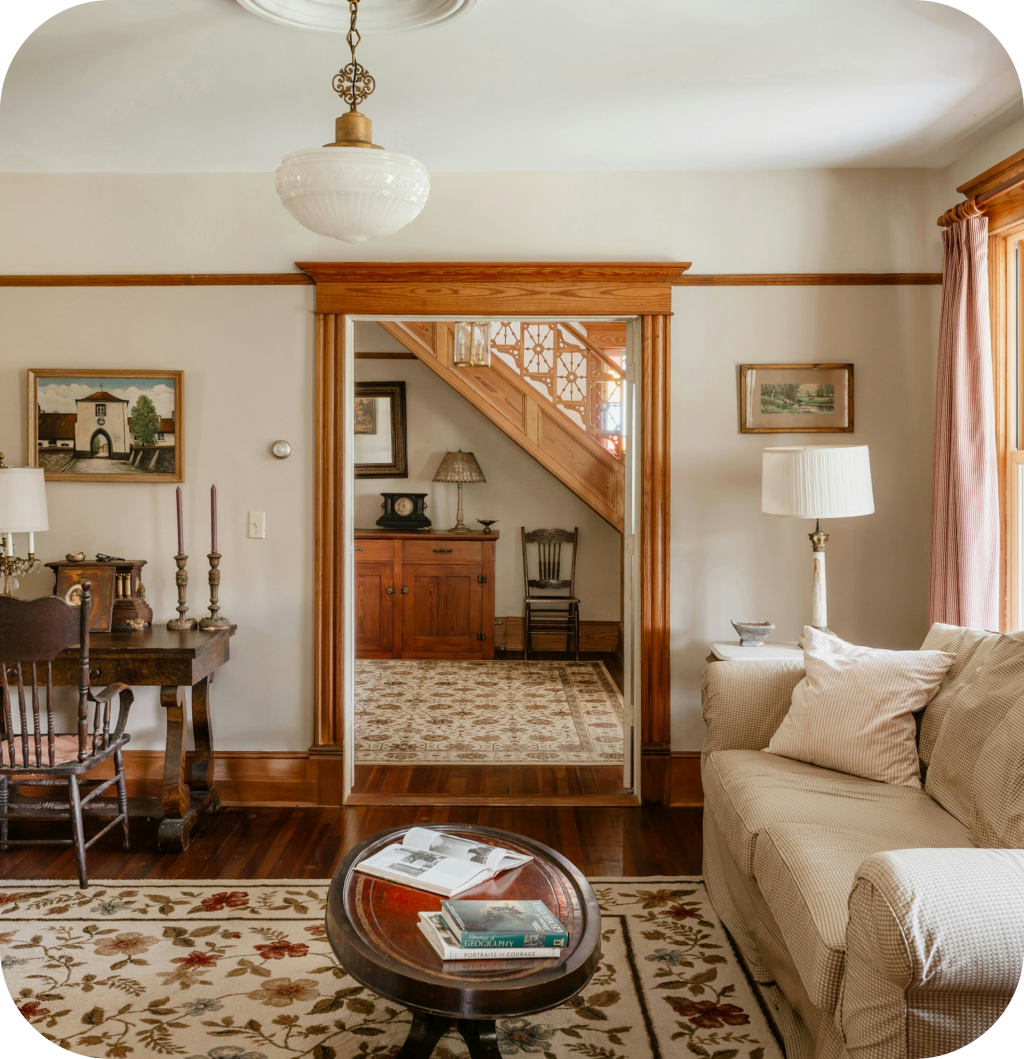 A Light Academia living room with a white sofa, a floral rug, a wooden coffee table and an antique light fixture.